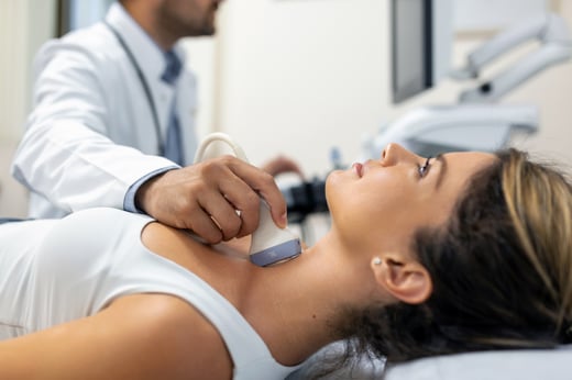 Woman laying on table while a technician does an ultrasound scan of her neck